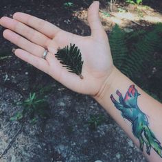 a person's hand with a tattoo on it and a small pine tree in the palm