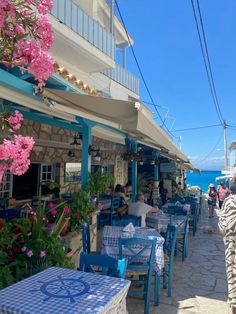 people are sitting at tables on the side of the road near an oceanfront restaurant