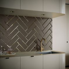 a modern kitchen with white cabinets and stainless steel backsplash, gold faucet