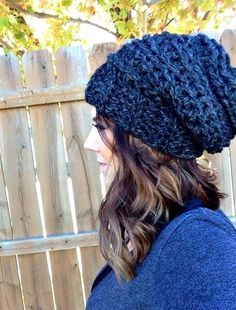 a woman wearing a black knitted hat next to a fence