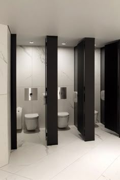 an empty bathroom with three stalls and two toilets in the corner, all black and white