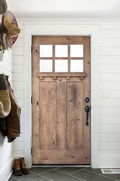 a wooden door sitting next to a white wall with boots hanging on it's hooks