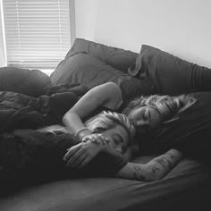 black and white photograph of two people laying on a bed with their arms around each other