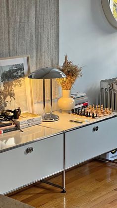 a living room with a table, lamp and pictures on the wall next to it