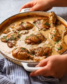 someone is holding a pan full of chicken and gravy