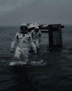 two astronauts are walking through the water