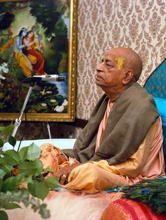 an old man sitting in front of a microphone and painting on the wall behind him