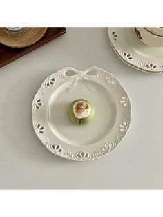 two white plates with small pastries on them, one is decorated with an ornament and the other has a bow