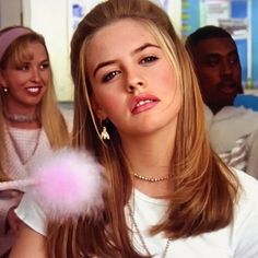 a girl blowing out a pink bubble with two other people in the background looking on