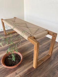 a wooden bench sitting on top of a hard wood floor next to a potted plant