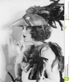 an old fashion photo of a woman wearing a hat with feathers on her head and holding a