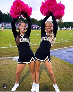 two cheerleaders are holding pink pom - poms in front of the camera