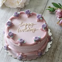 a pink birthday cake sitting on top of a wooden table