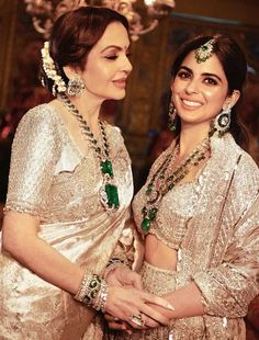 two women dressed in gold and green are standing next to each other with jewelry on their heads