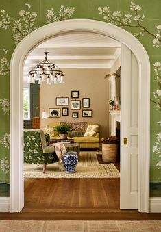 a living room with green walls and white flowers on the wall behind the couches