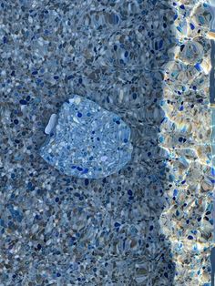 an aerial view of the surface of a swimming pool with blue and white tiles on it