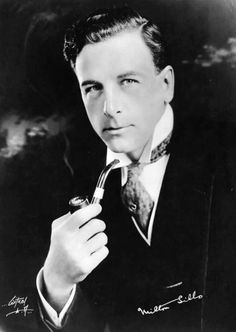 black and white photograph of a man with a tie holding a pipe in his hand