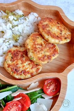 two crab cakes and rice in a wooden bowl on a white tablecloth with tomatoes