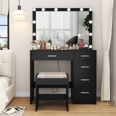 a dressing table with lights on it in front of a window and a white couch