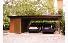 two cars are parked under a wooden carport