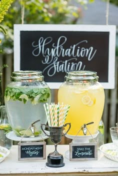 a table topped with drinks and food on top of a white table covered in signs