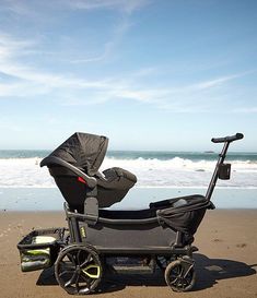 a baby stroller sitting on the beach next to the ocean