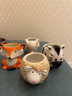 four ceramic animal cups sitting on top of a table