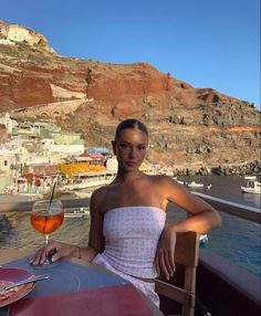 a woman sitting at a table with a glass of wine in front of her on the water