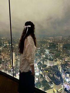 a woman standing on top of a tall building looking down at the city below her