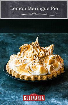 a pie with meringue on top sitting on a black plate next to a blue background