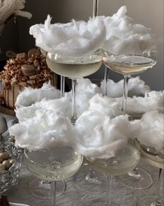 three glasses filled with white wine and cotton floss on top of each glass, sitting on a table