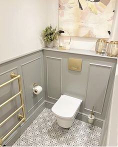 a white toilet sitting in a bathroom next to a gold radiator and towel rack