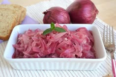 a white bowl filled with red onions next to two slices of bread on top of a table