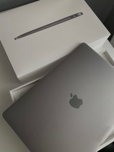 an apple laptop sitting on top of a white box next to a macbook pro