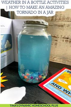 a jar filled with blue liquid sitting on top of a table next to an open book