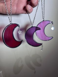 two pieces of jewelry are being held by someone's hand with the moon and crescent pendants on them