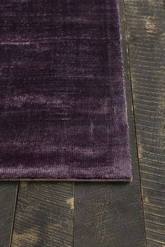 a purple rug is laying on the floor with wood planks in front of it