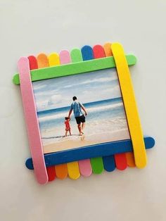 a colorful frame with a man and child walking on the beach