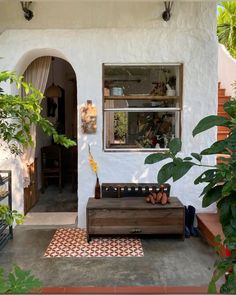 a white house with a wooden bench and potted plants