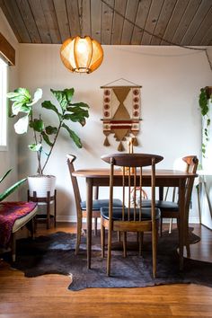 a dining room table and chairs with plants on the wall