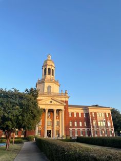 a tall building with a clock tower in the middle of it's front yard