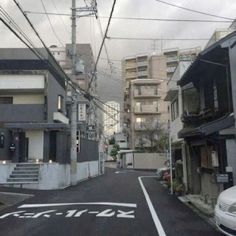 an empty street with cars parked on the side and buildings in the backround