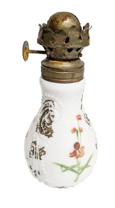 an old fashioned oil bottle with flowers painted on it's side and a brass top