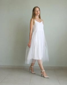 a woman in a white dress is posing for the camera