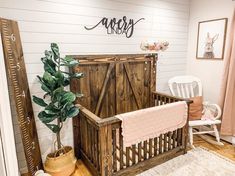 a baby's room with a crib, rocking chair and potted plant