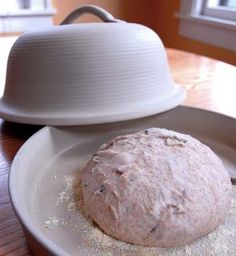 a white plate topped with a doughnut on top of a wooden table next to a bowl