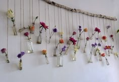 vases filled with flowers are hanging on the wall in front of a string sculpture