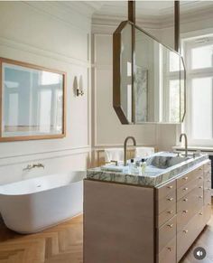 a bathroom with a tub, sink and large mirror in the corner next to it