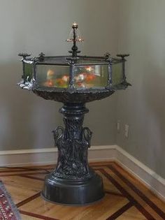 a water fountain with three lit candles in it on the floor next to a potted plant