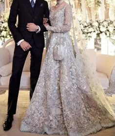 the newly married couple pose for a photo in their lavish wedding gowns and veils